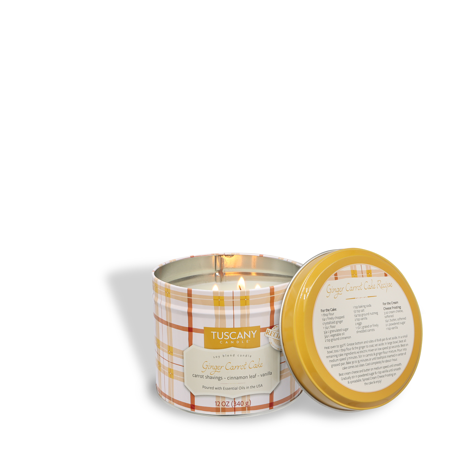 A lit Tuscany Candle® SEASONAL "Ginger Carrot Cake: Spice Cake & Sugar" (12 oz) Bakery Tins Collection sits beside its yellow lid, which displays a ginger carrot cake recipe.