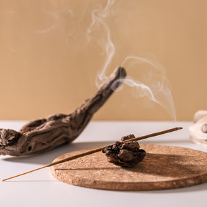 A still life photo of sandalwood and incense, two of the prominent fragrance notes found in the "Smoked Sandalwood" scented candle from Tuscany Candle's "Homme & Heritage" collection