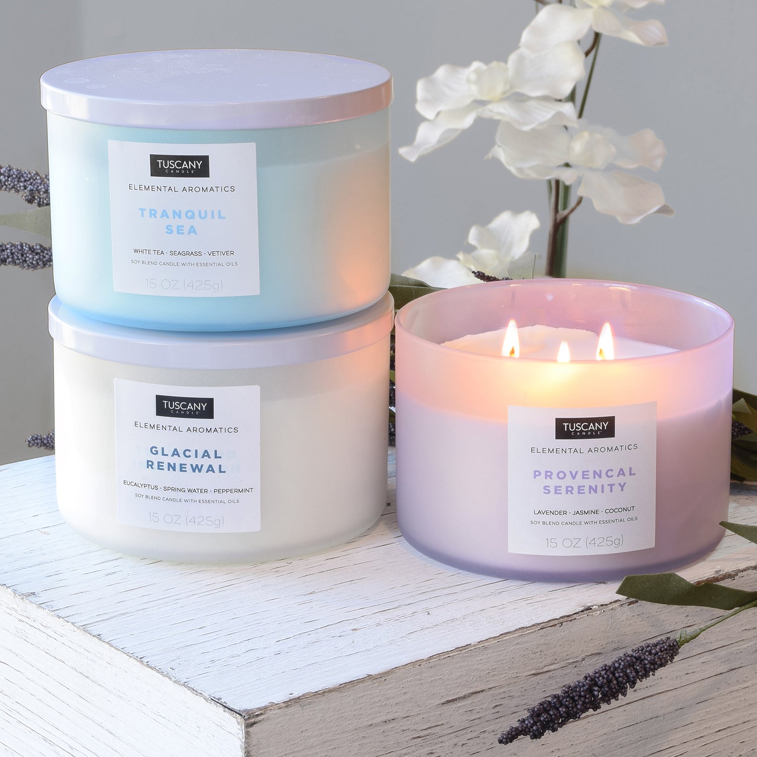 Three jars of Tranquil Sea Scented Jar Candles (15oz) from the Elemental Aromatics Collection, by Tuscany Candle® EVD, on a table.