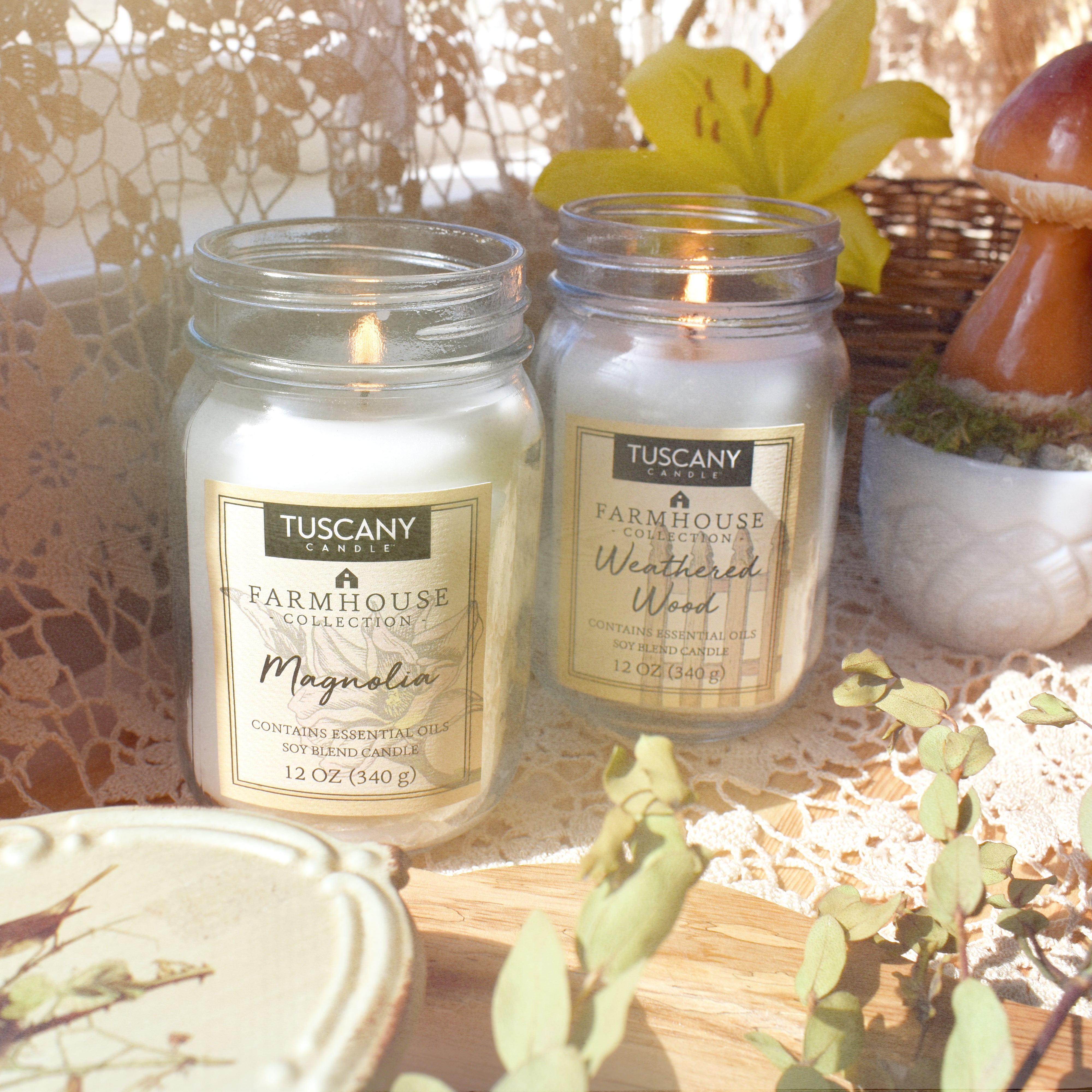 Two jars of Weathered Wood Scented Jar Candle (12 oz) – Farmhouse Collection by Tuscany Candle are sitting on a weathered wood table.