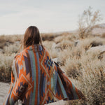 Load image into Gallery viewer, A meditative photo of a woman wrapped in a blanked on a tranquil desert morning. This photo inspires Tuscany Candle&#39;s Fragrance &quot;Desert Detox&quot;
