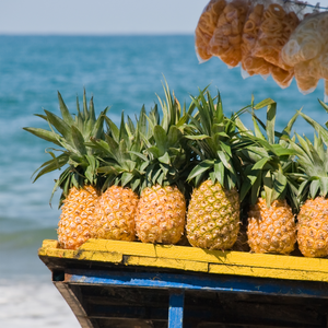 A cart of pineapples in a beachfront tropical market. Scense such as this are the inspiration for our "Caribbean Market" fruit-scented candle.