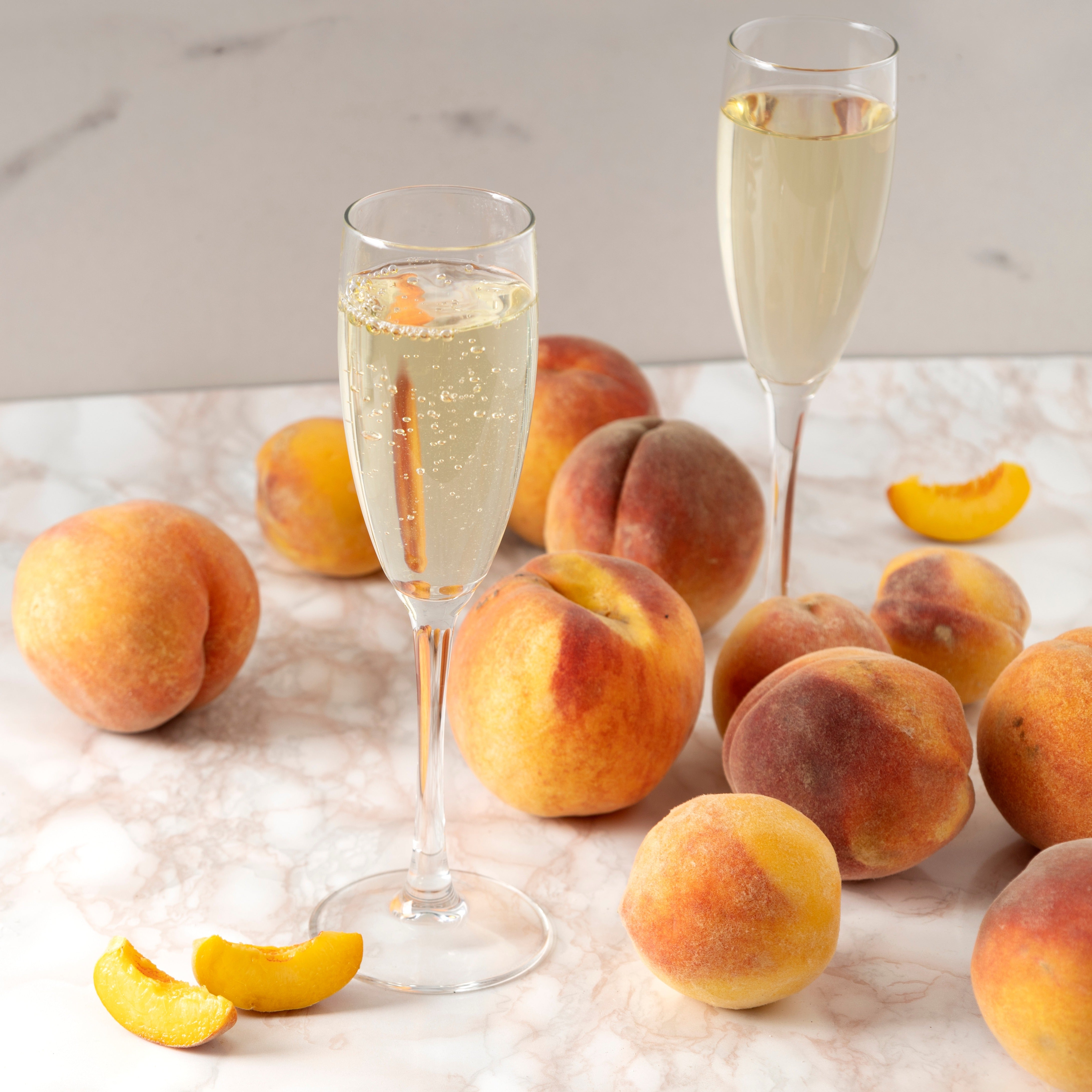 A Peach Prosecco scented wax melt bar, released by Tuscany Candle®, releasing sweet fragrance notes, sitting alongside a scented candle on a marble table.