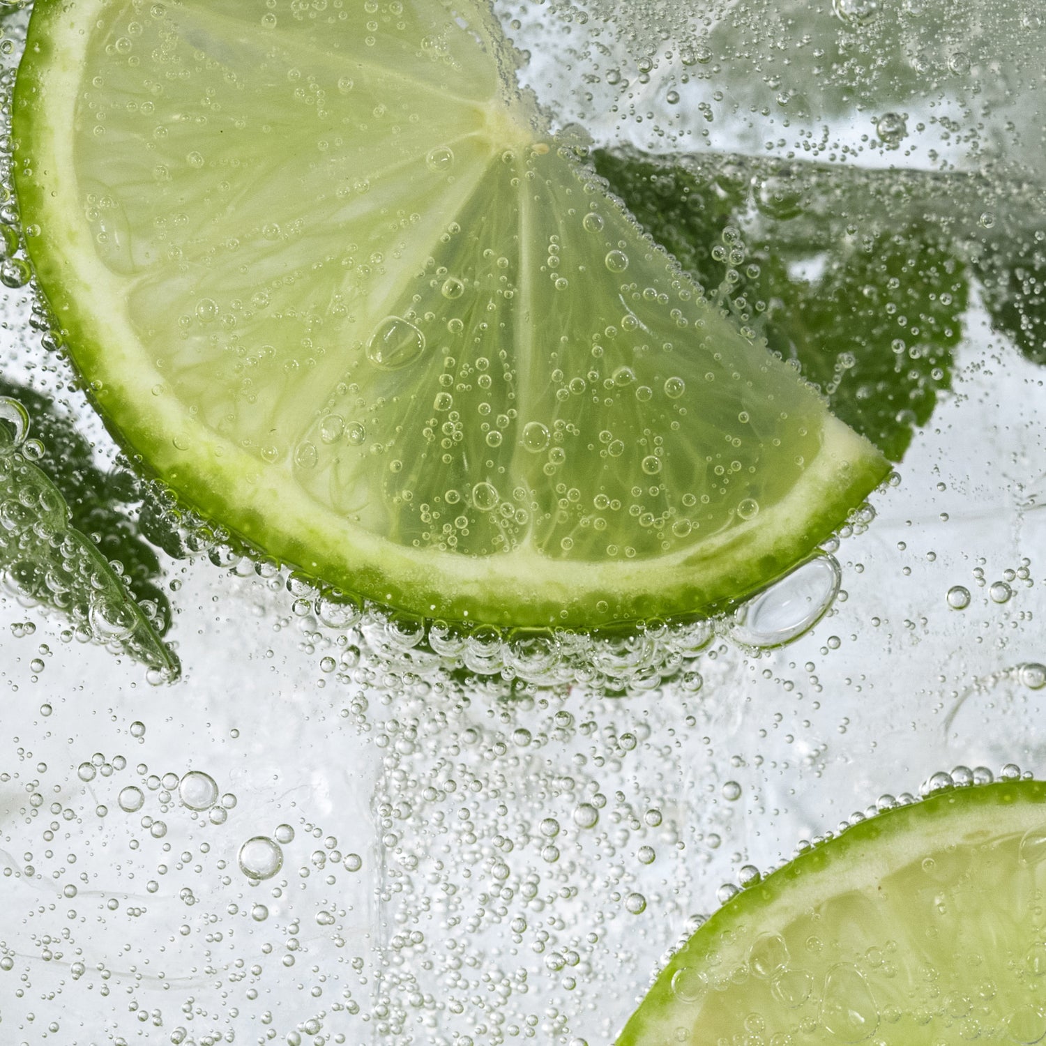 A close up of lime slices and ice cubes, creating a refreshing and invigorating Pomegranate Fizz Long-Lasting Scented Jar Candle (14 oz) by Tuscany Candle.