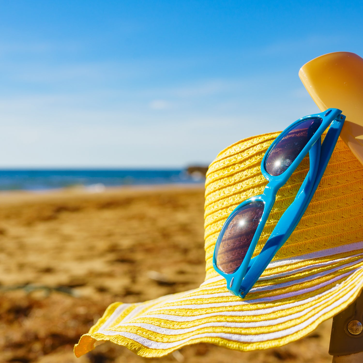 A hat and sunglasses rest on a sunny beach - inspiration for our "Cabana" wax melt scent