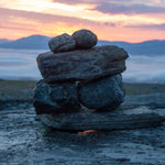 Load image into Gallery viewer, A photo of tranquil stacked rocks warming on a cold mountain morning, which is a sensation we are trying to evoke with our &quot;Tundra Meditiation&quot; scented candle
